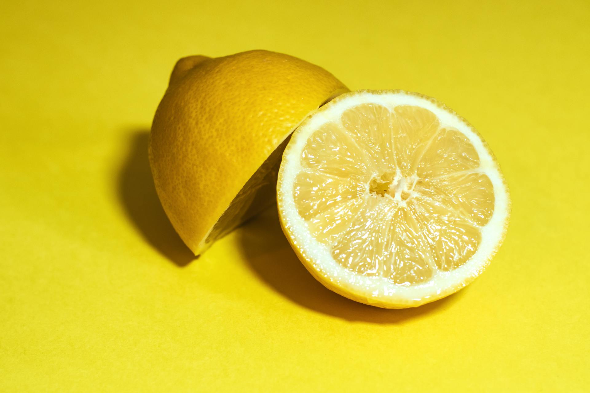 Halbierte frische Zitrone auf gelbem Hintergrund – Symbol für die klare, spritzige Frische von ätherischem Zitronenöl.
