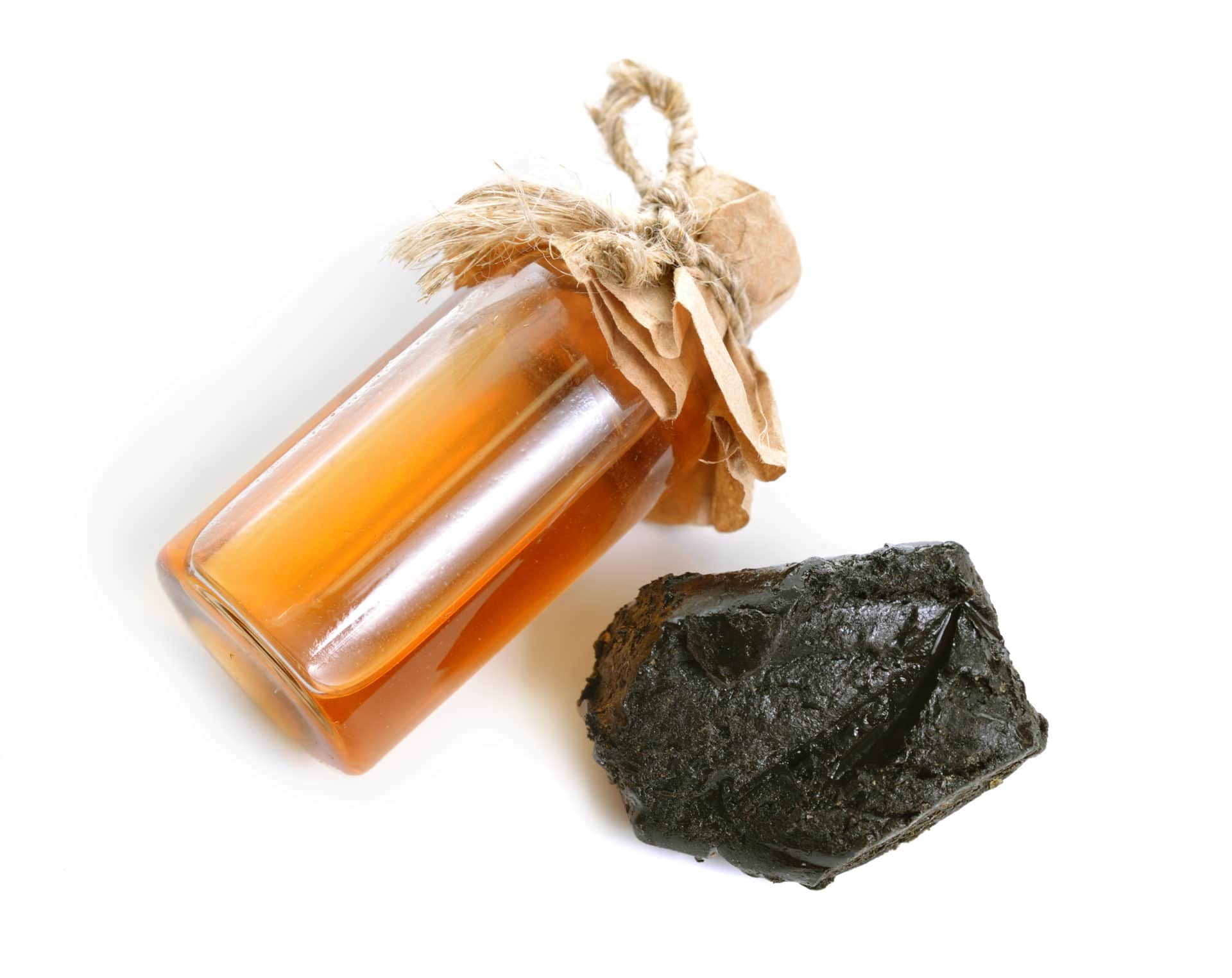 abdanum-Harz in fester und flüssiger Form – eine bernsteinfarbene Glasflasche mit duftender Labdanum-Absolue neben einem dunklen, harzigen Brocken auf weißem Hintergrund.