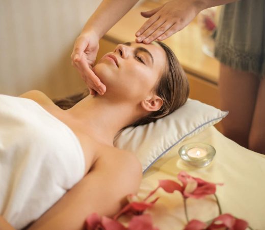 Frau bei entspannender Wellness-Anwendung mit Duftkerze und Blüten – ideal für aromatische DIY-Roll-Ons mit ätherischen Ölen