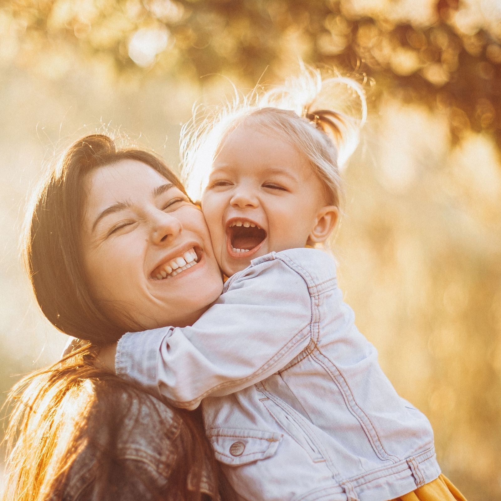 Mutter und fröhliche Tochter lachen gemeinsam in goldenem Sonnenlicht – ein Moment voller Geborgenheit und Lebensfreude