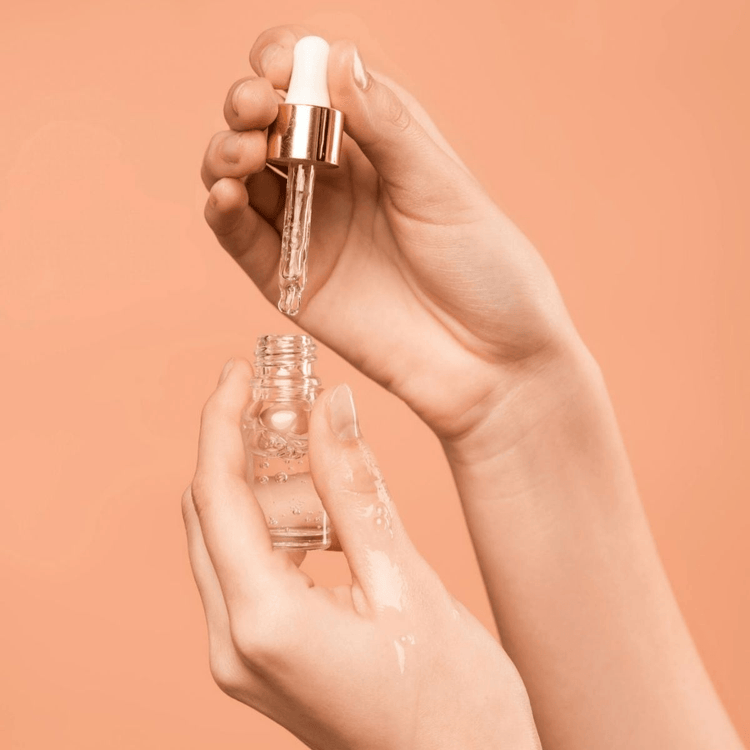 Hand hält eine Pipette mit Ingweröl über einer Glasflasche – Symbol für sorgfältige Dosierung und sichere Anwendung ätherischer Öle.