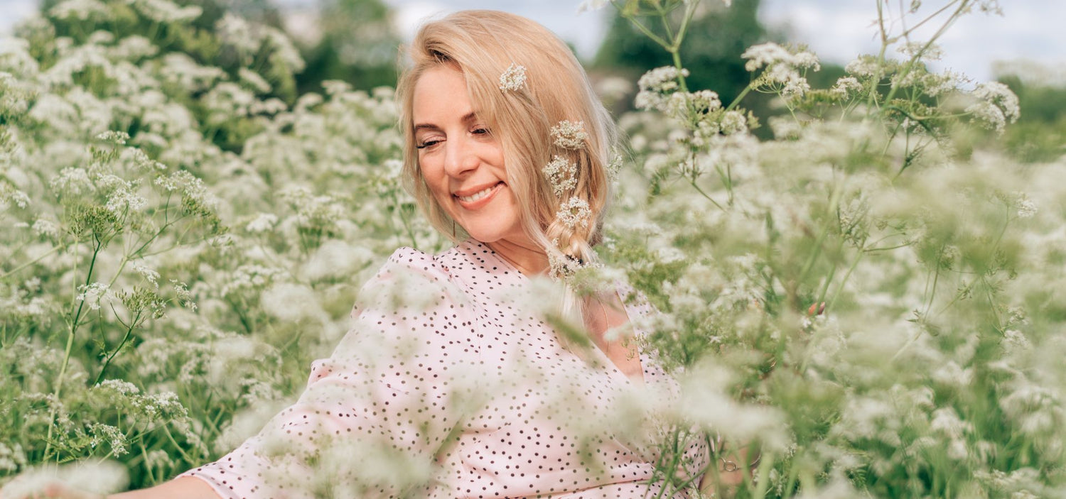 Lächelnde Frau im weißen Blütenfeld – ein Moment voller Leichtigkeit, Naturverbundenheit und weiblicher Lebensfreude