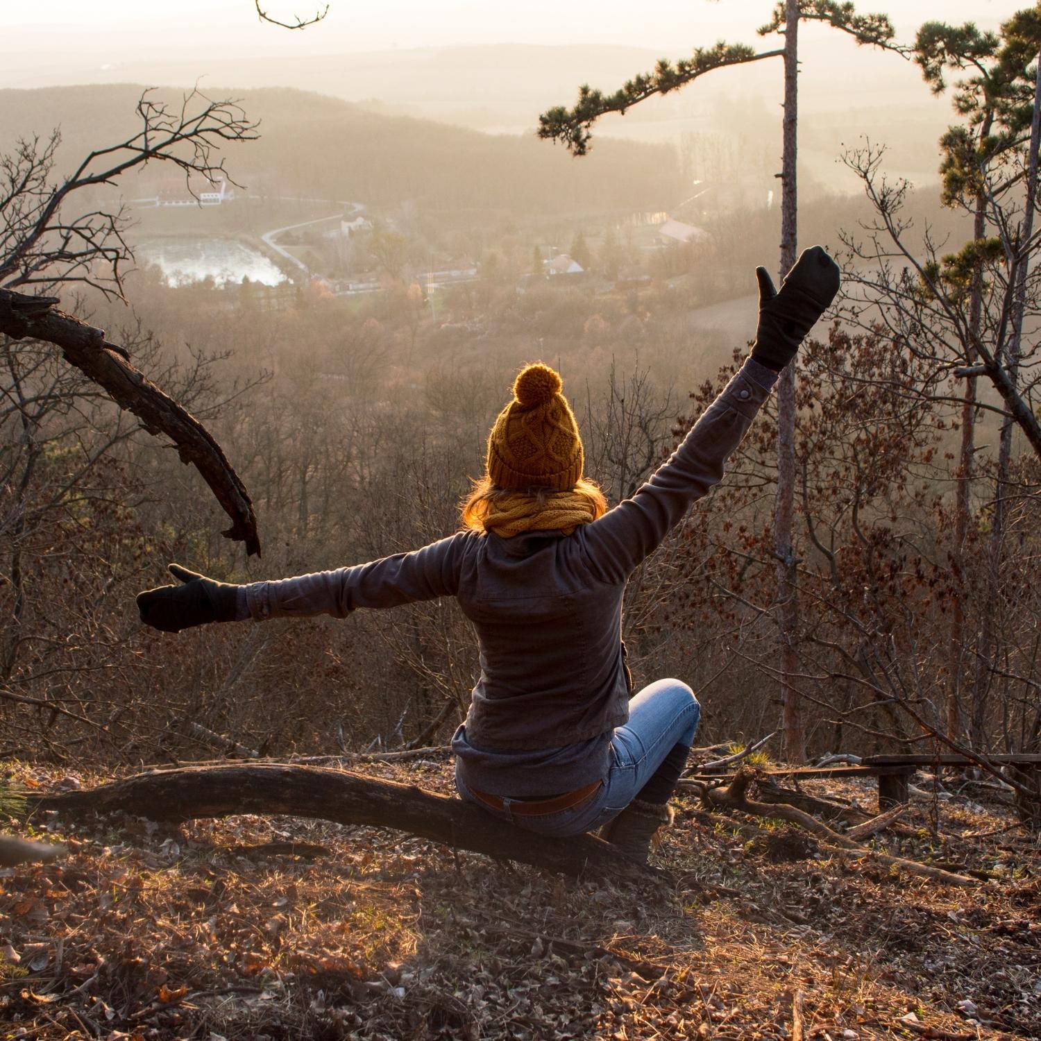 Frau im Sonnenaufgang mit ausgebreiteten Armen im Kiefernwald – Symbol für Freiheit und naturreine Kieferöle von ESSENCE-PUR