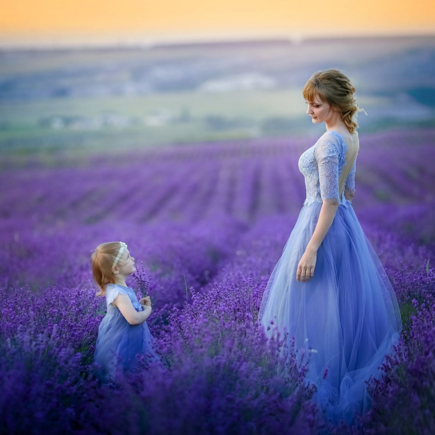 Mutter und Tochter in eleganten blauen Kleidern im Lavendelfeld bei Sonnenuntergang – poetische Atmosphäre voller Verbundenheit, Liebe und Lavendel – ESSENCE-PUR
