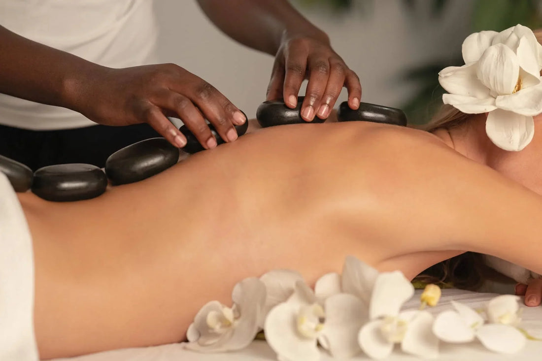 Frau bei entspannender Aromatherapie-Massage mit Hot-Stones und weißen Blüten