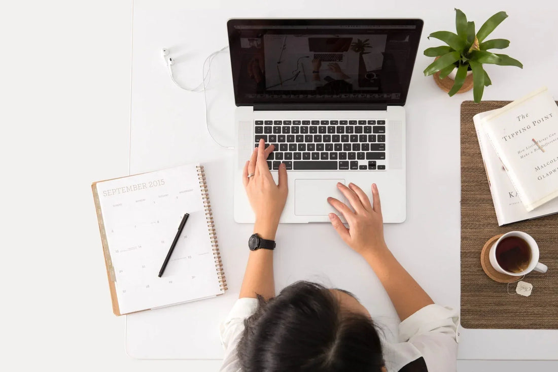 Lernende Person am Laptop mit Kalender, Tee und Buch – Fokus und Ruhe beim Lernen