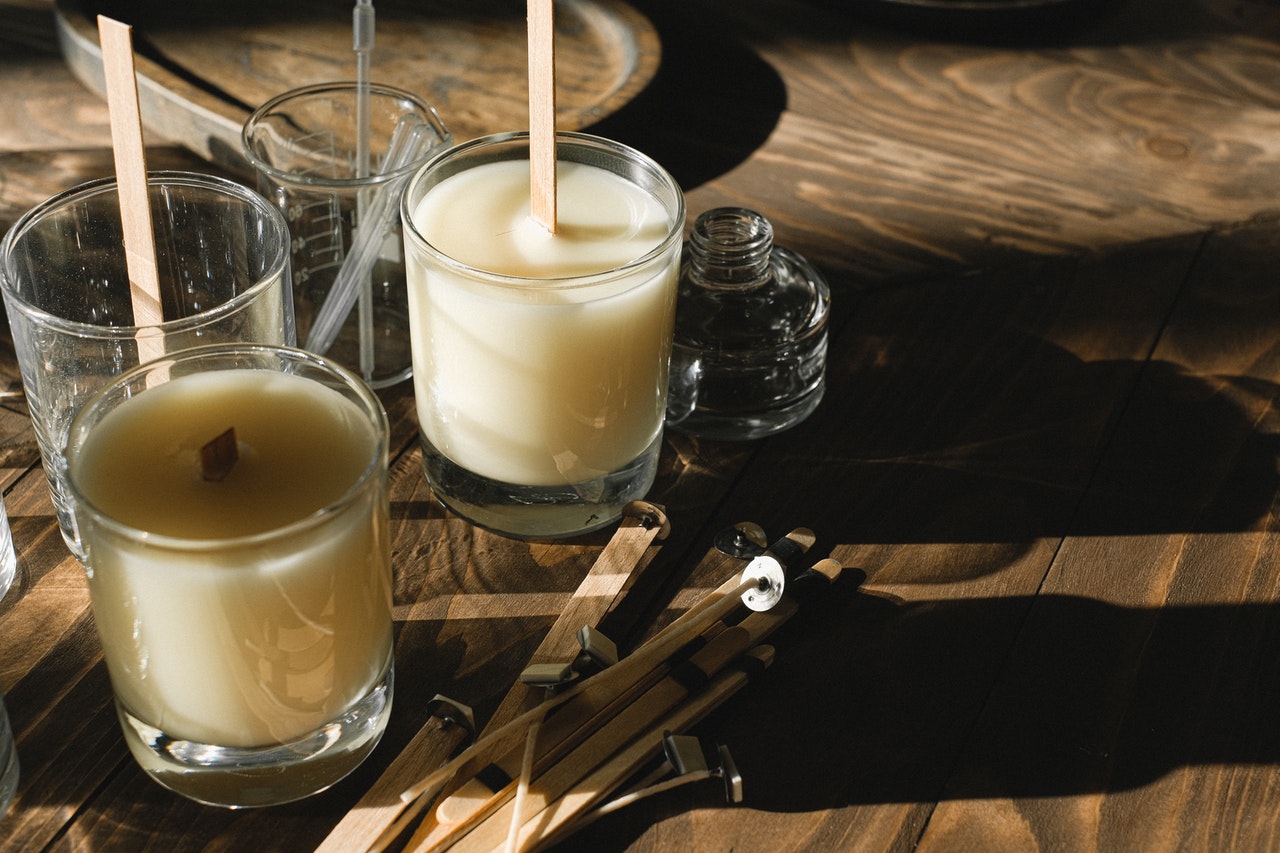 DIY-Citronella-Kerzen in Gläsern mit Dochten, vorbereitet auf einem Holztisch – natürliche Mückenabwehr mit ätherischen Ölen