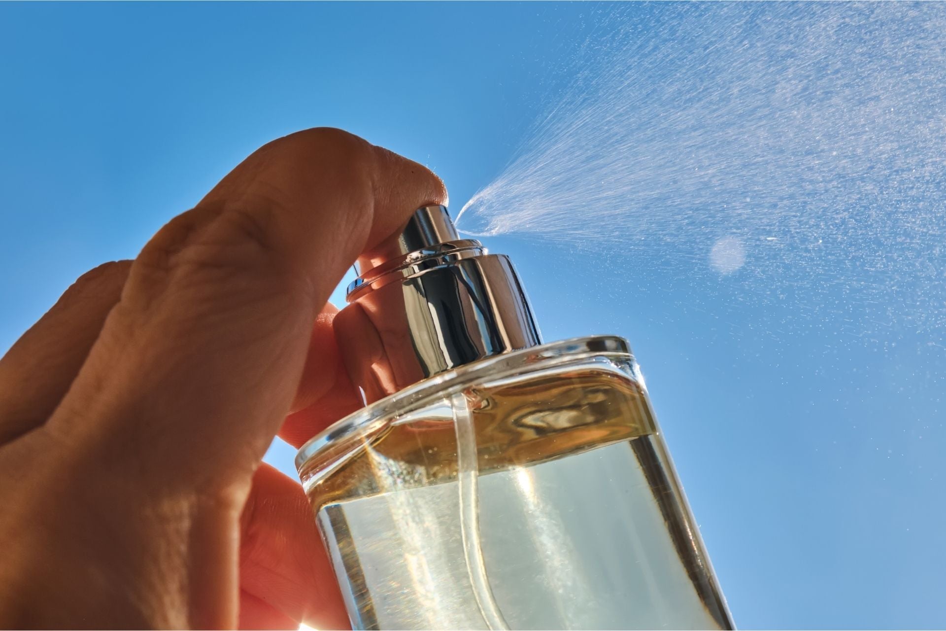 Hydrolat-Anwendung als erfrischender Gesichtsspray vor blauem Himmel – sanfte Pflanzenpflege natürlich angewendet