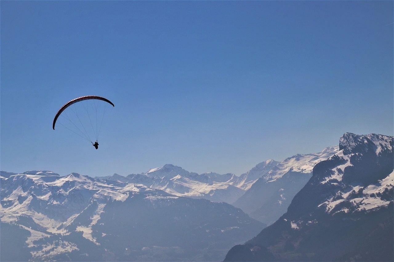 Paraglider vor majestätischer Alpenkulisse mit klarem Himmel – Symbol für Freiheit, Energie und Weitblick.