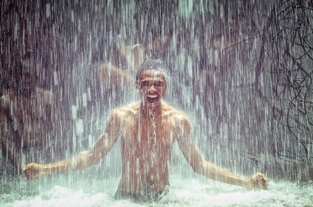 Mann unter einem Wasserfall als Symbol für natürliche Frische, klare Luft und belebende Natur – Stimmungsbild zur Duftmischung FRISCHE von ESSENCE-PUR