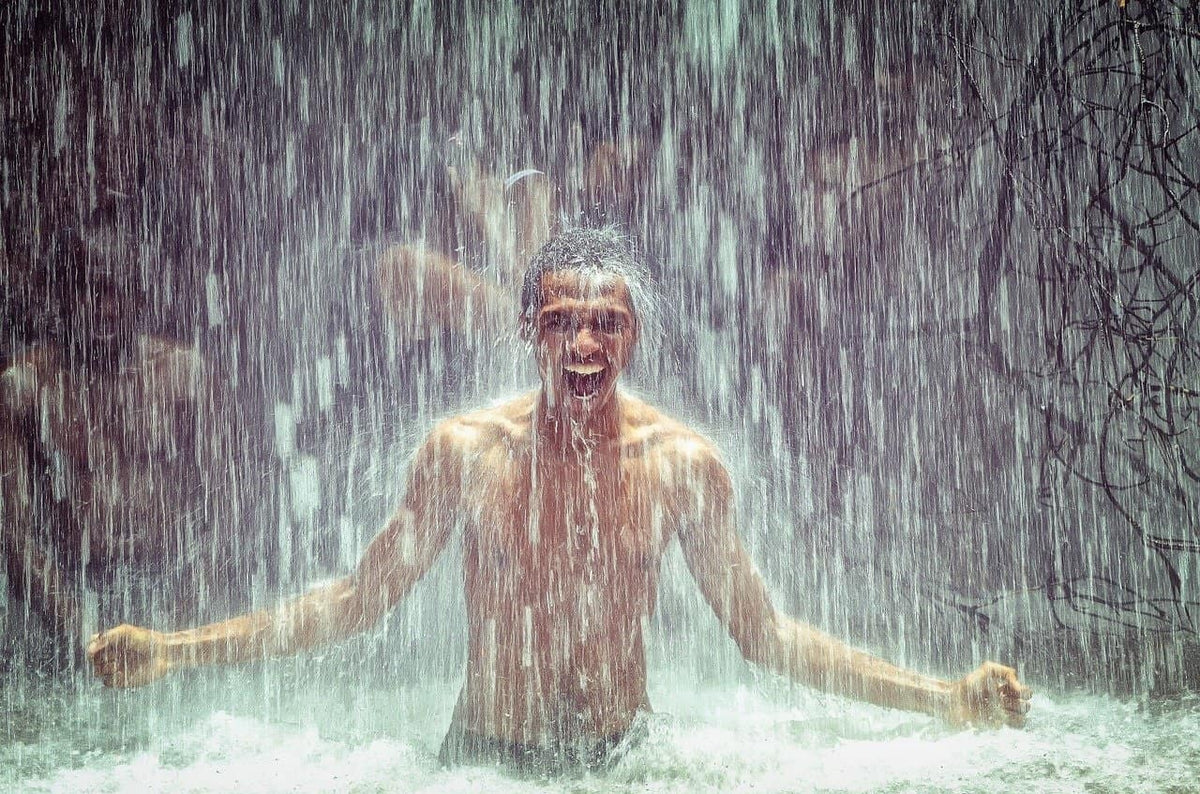 Mann unter einem Wasserfall als Symbol für natürliche Frische, klare Luft und belebende Natur – Stimmungsbild zur Duftmischung FRISCHE von ESSENCE-PUR