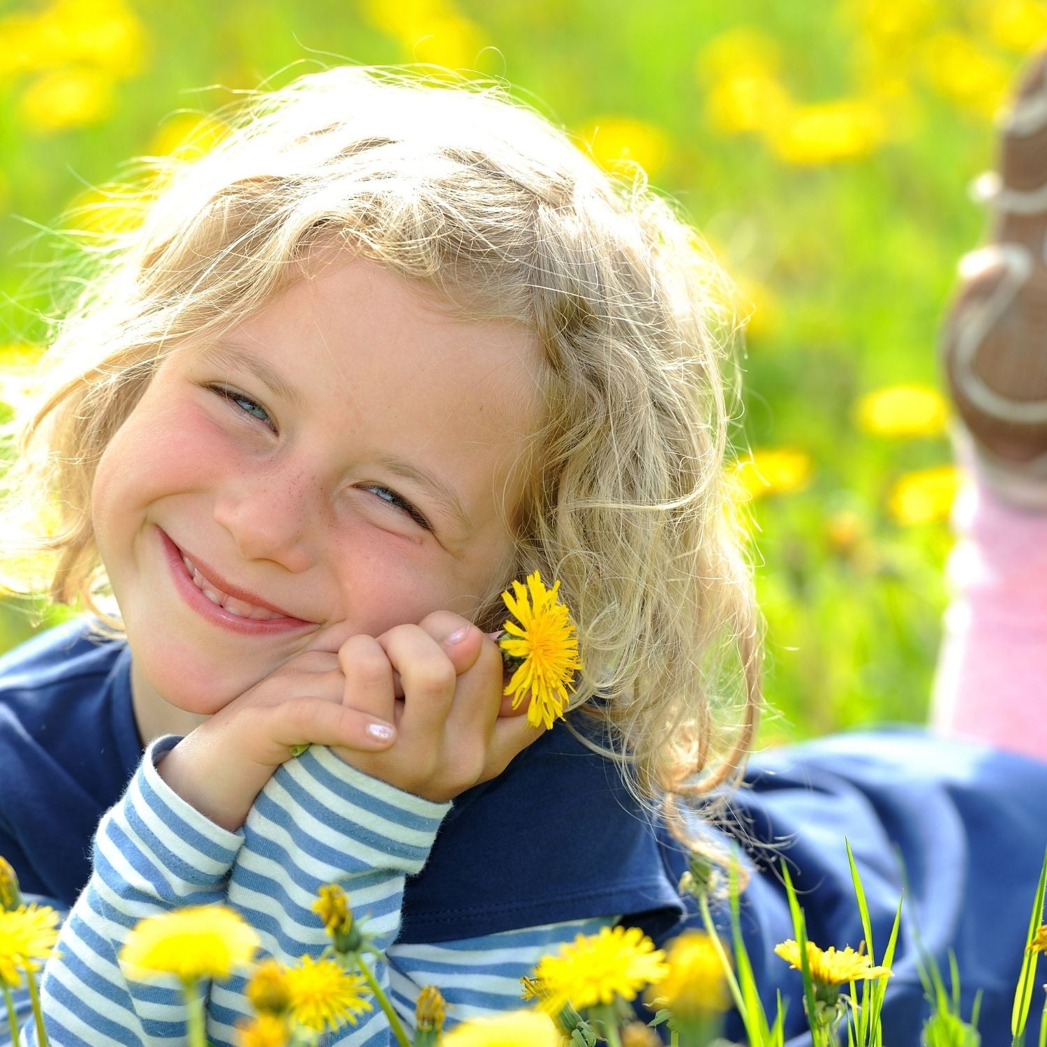 Fröhliches Kind auf einer Blumenwiese mit Löwenzahn – Symbol für Leichtigkeit, Freude und natürliche Düfte von ESSENCE-PUR