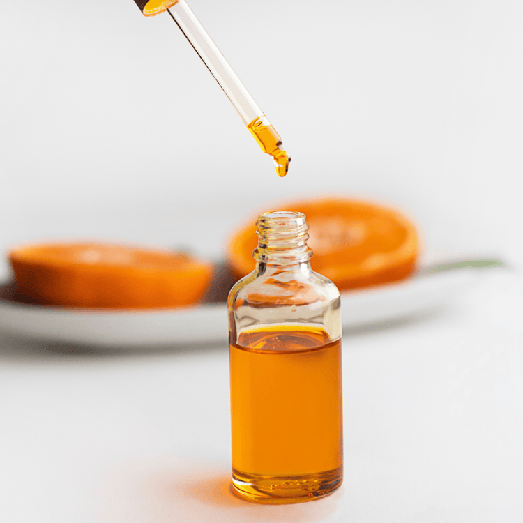 Glasflasche mit orangefarbenem ätherischem Mandarinenöl und Pipette, im Hintergrund aufgeschnittene Mandarinen – Symbol für die Gewinnung und Anwendung des naturreinen Mandarinenöls.