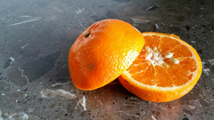 Aufgeschnittene Orange mit Kernen auf Steinplatte – Grundlage für naturreines Orangenöl