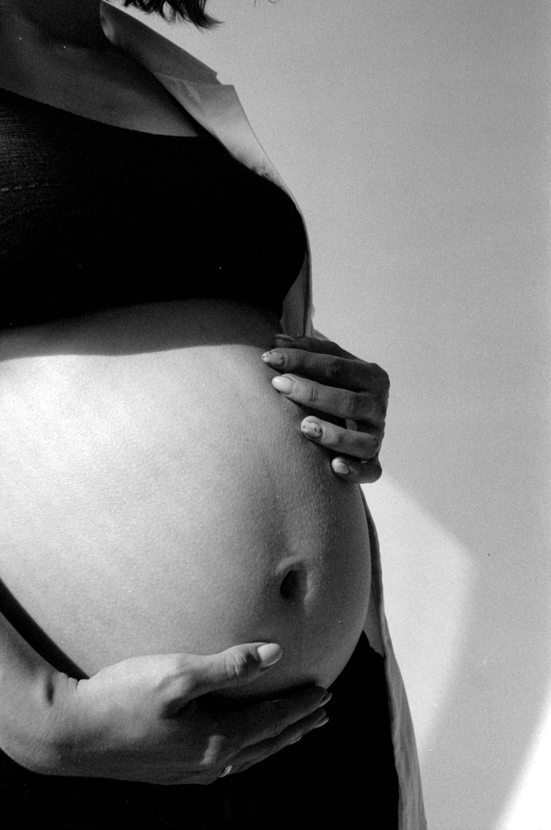 Wunder des Lebens – Nahaufnahme eines Babybauchs in liebevoller Umarmung.