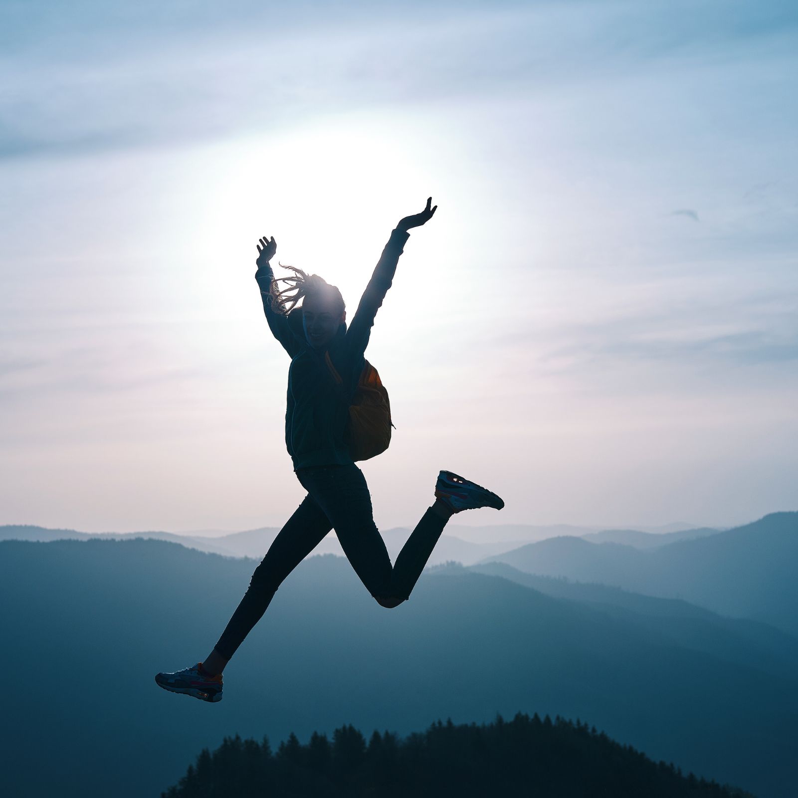 Frau springt voller Lebensfreude und Energie vor leuchtender Sonne – Symbol für Vitalität, Leichtigkeit und Lebenslust.