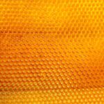 Nahaufnahme einer goldgelben Bienenwabe – natürliche Struktur des Bienenwachses.